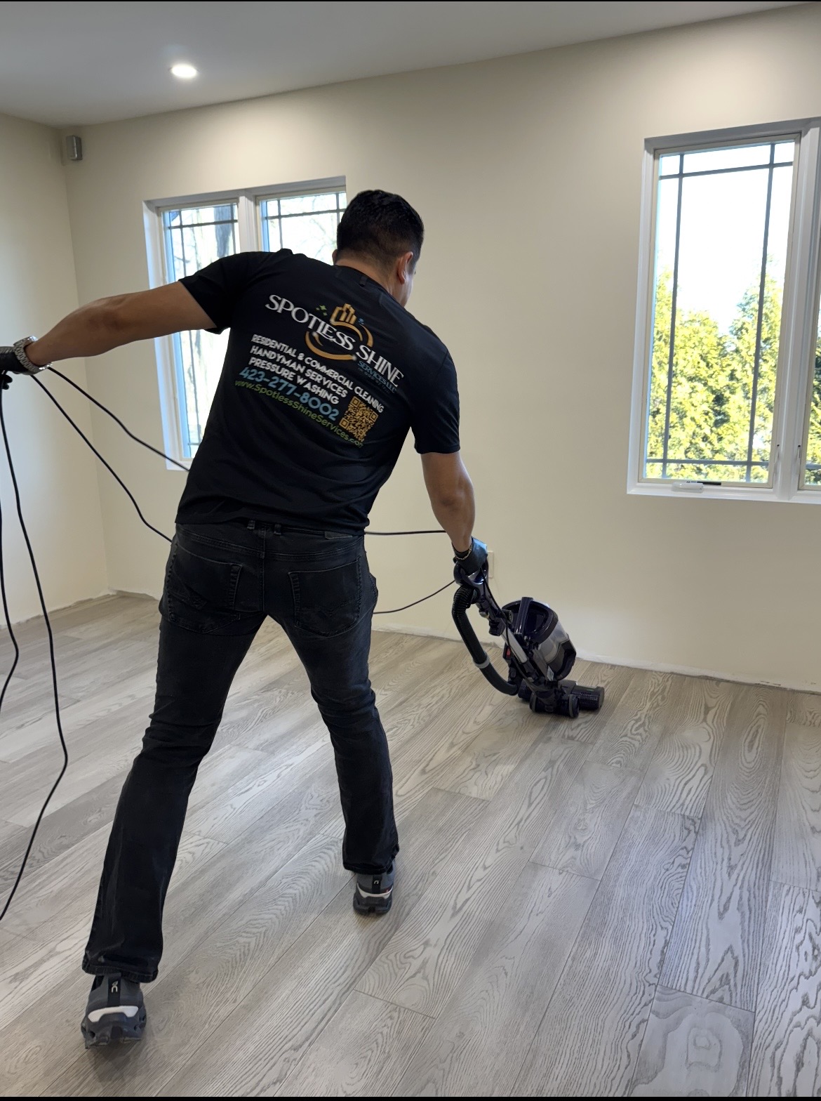Spotless Shine team member vacuuming hardwood floors in a freshly cleaned room
