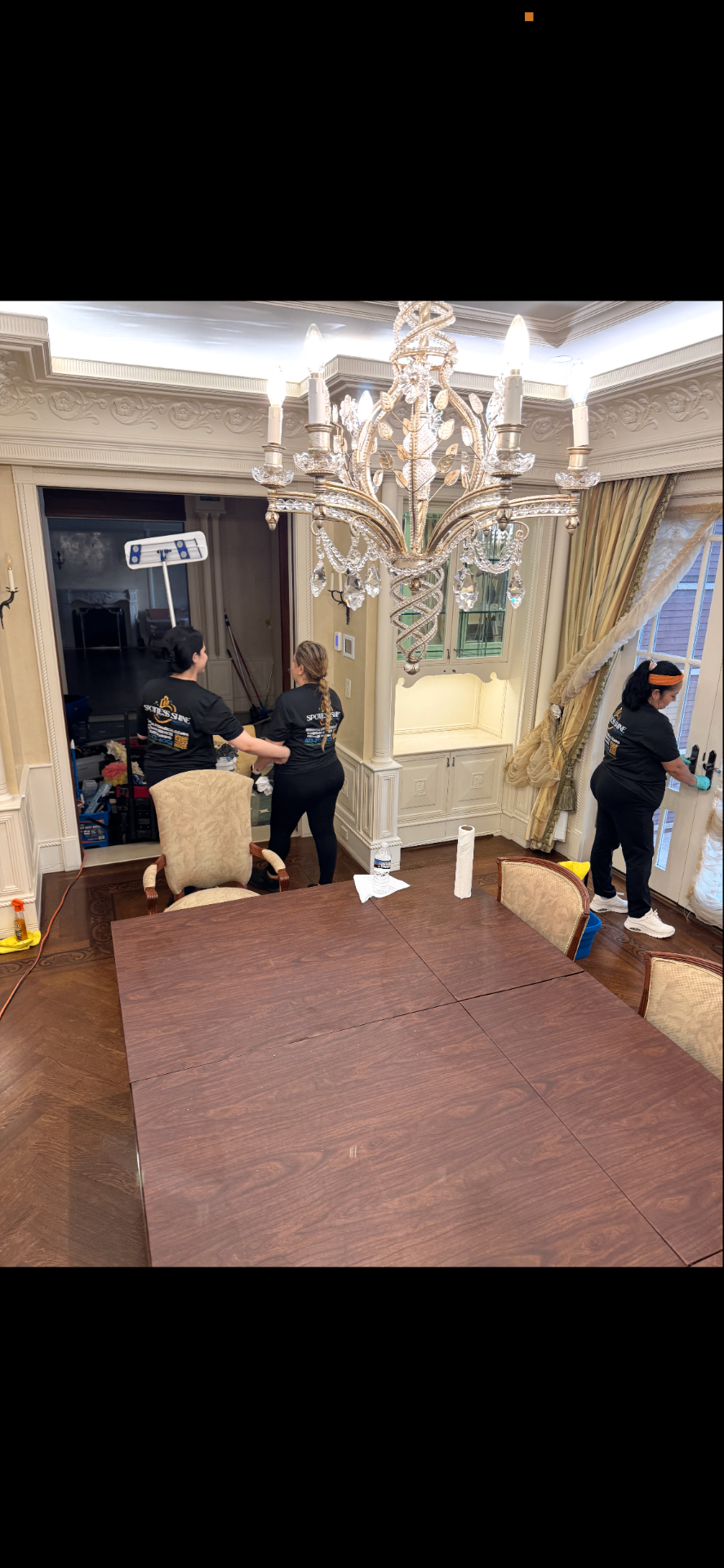 Spotless Shine team deep cleaning an elegant dining room with crystal chandelier